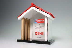 House-shaped acrylic and wood deal toy marking private equity acquisition in real estate sector.