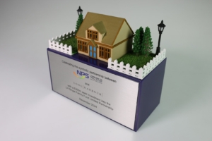 Bespoke real estate deal toy with miniature house and landscaped base celebrating strategic investment partnership.