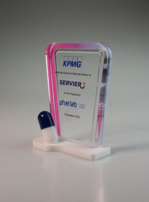 Acrylic financial tombstone marking Servier disposal, featuring layered colour acrylic and capsule detail.